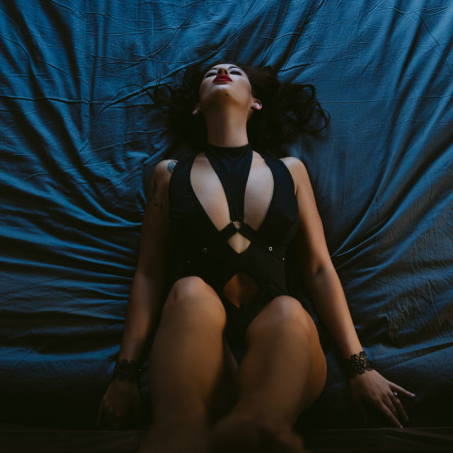 A woman in black lingerie laying on a bed.